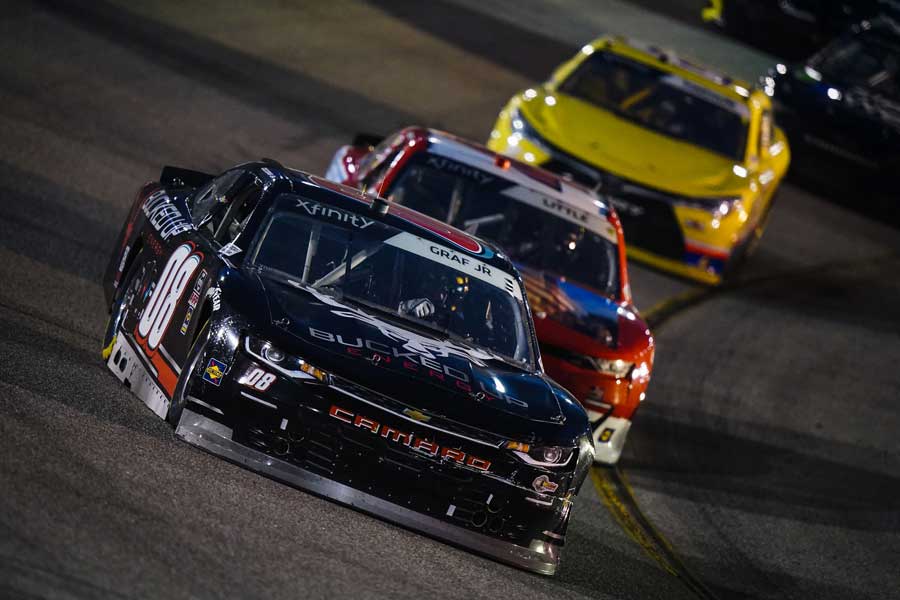 Photo of 3 race cars racing on a track at night.