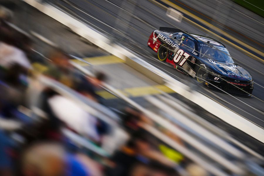 Photo of race car 07 racing on track with grounds blurred