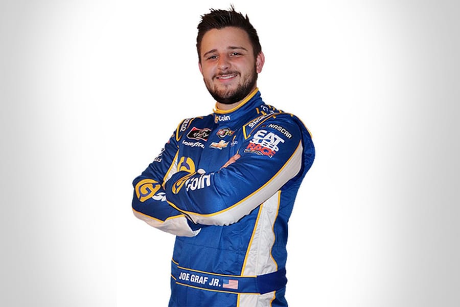 Man standing with arms crossed in blue race suit